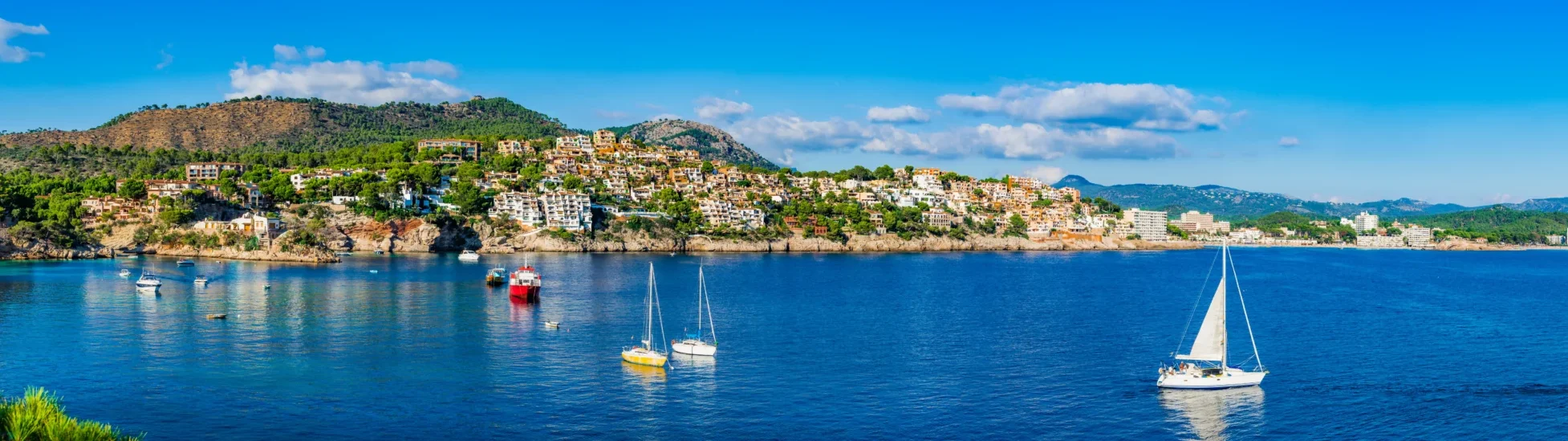 Bright blue waters with yachts in it cruising around the coast on a sunny