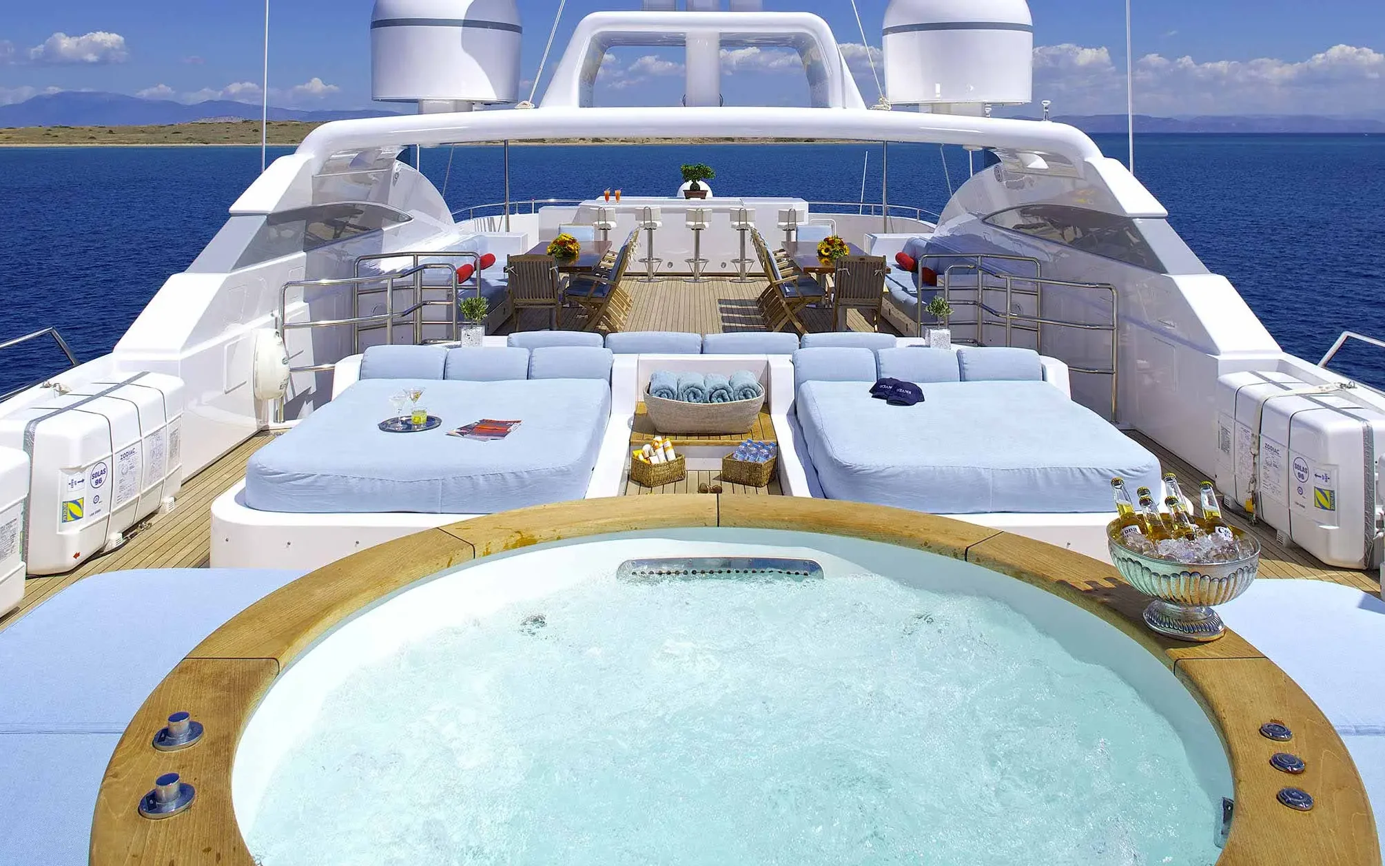Exterior of the Oceanos yacht with a jacuzzi and lounge sofas with chairs and tables in the background.