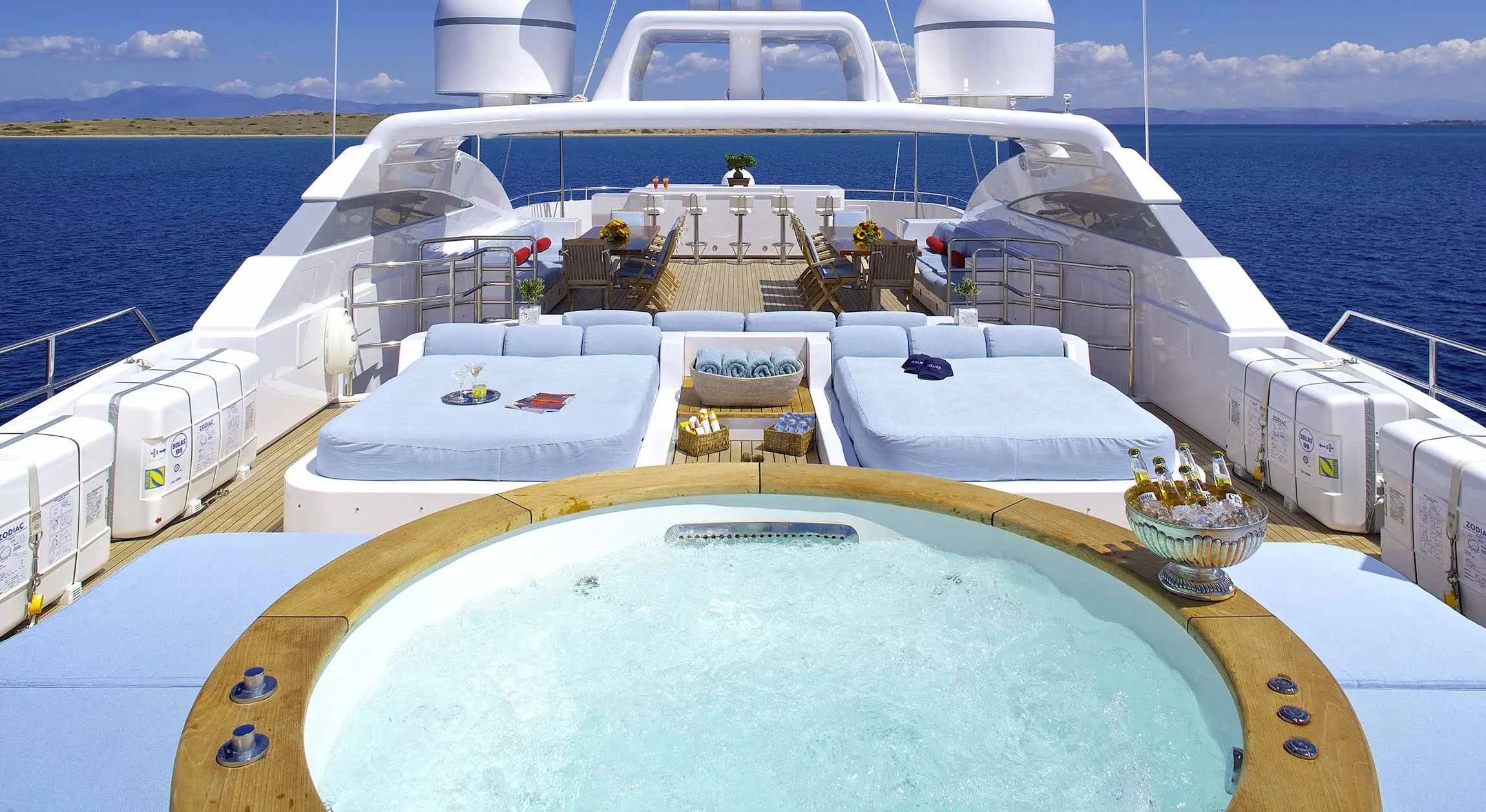 Oceanos Yacht Exterior of the Oceanos yacht with a jacuzzi and lounge sofas with chairs and tables in the background.