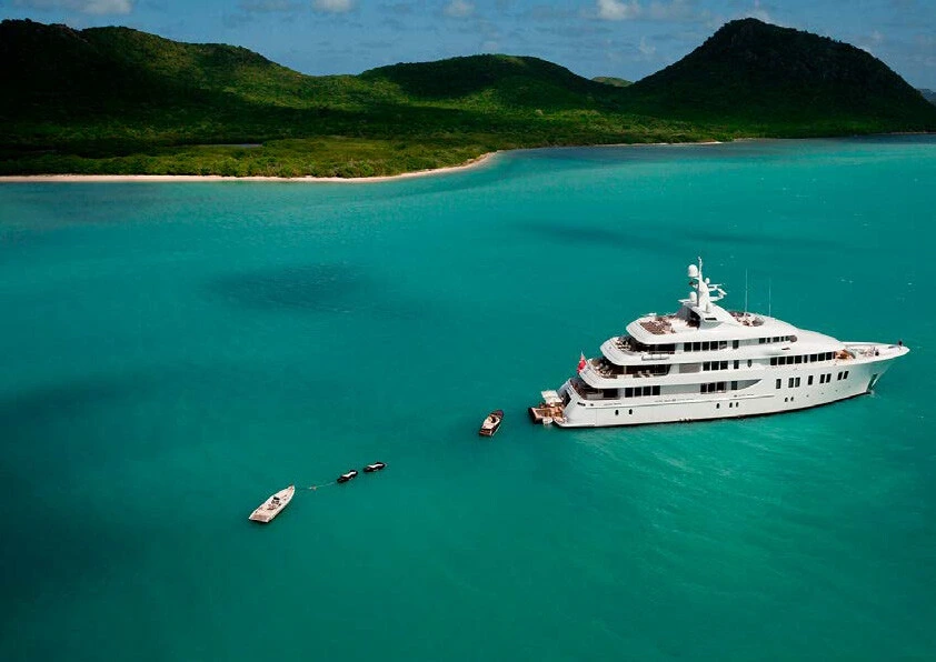 A superyacht just offshore the Leeward Islands in turquoise waters.