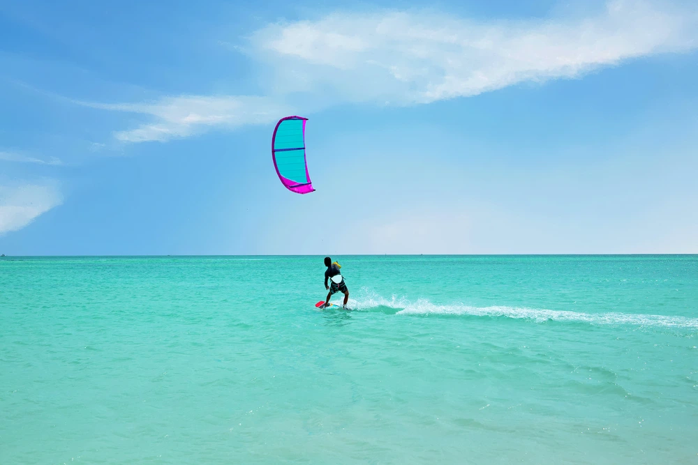 A man windsurfing on bright blue waters on a clear day.