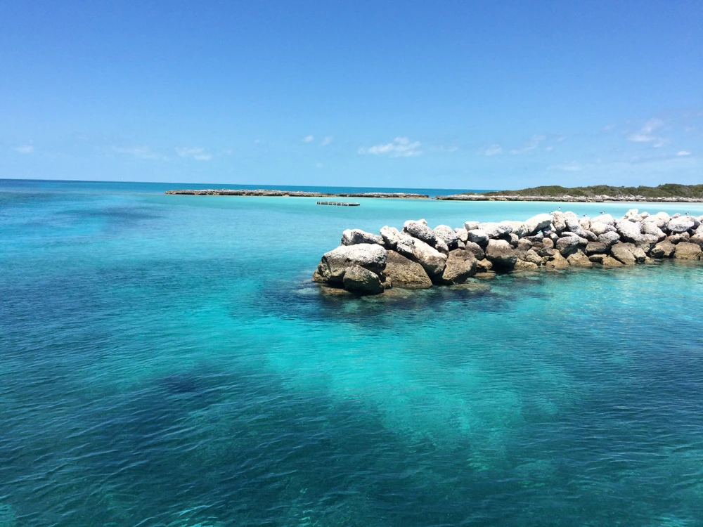 Rocky pier of Highbourne Cay leading out into turquoise waters.