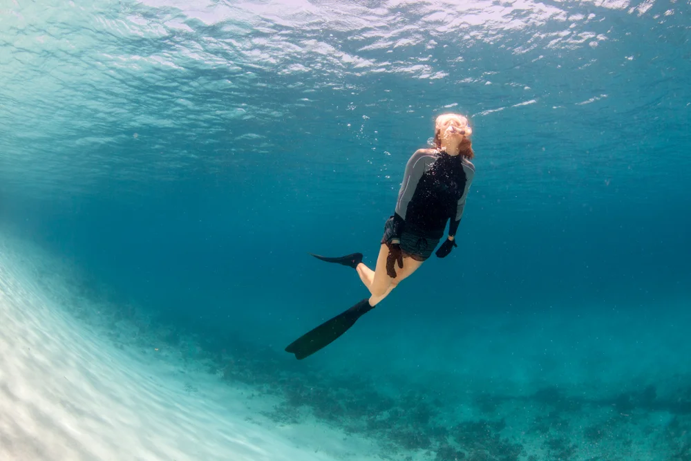 A woman snorkelling underwater in clear blue water.