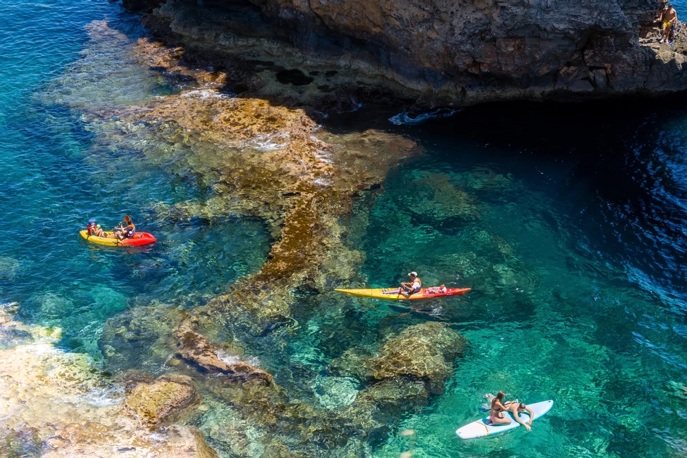 Three people kayaking over turquoise waters.