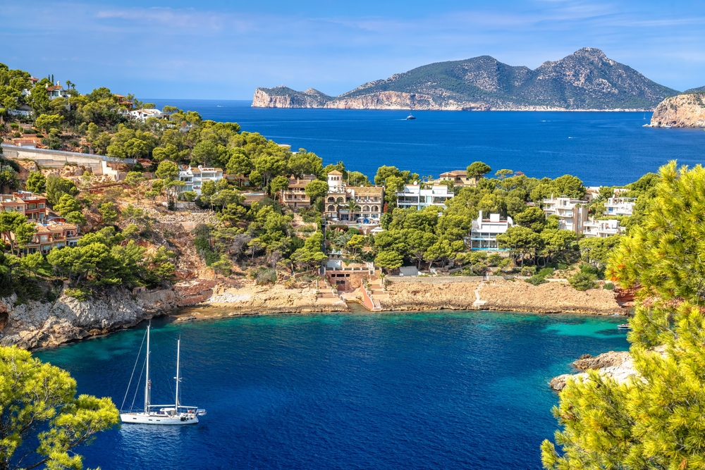 Puerto Andraitx with a yacht on clear blue waters.