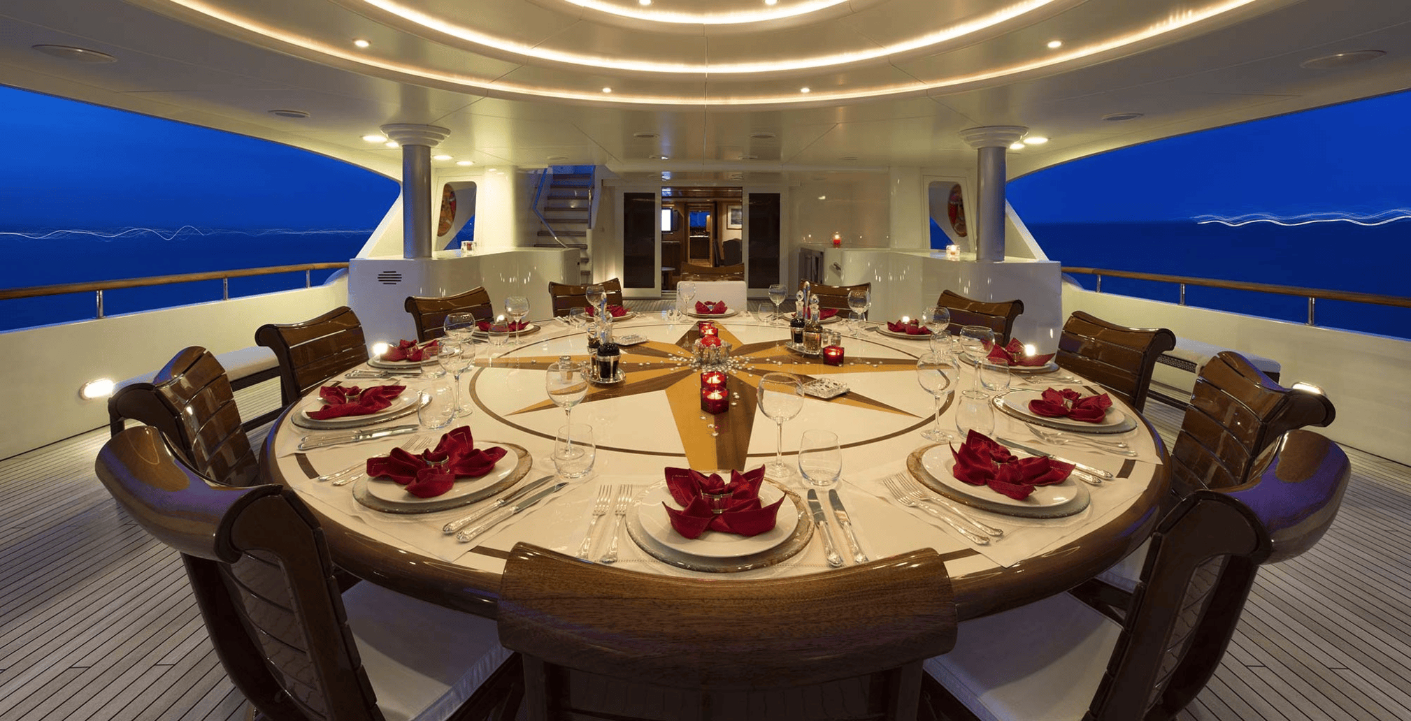 Set Tables on Yacht Superyacht interior table with luxury table settings at night.